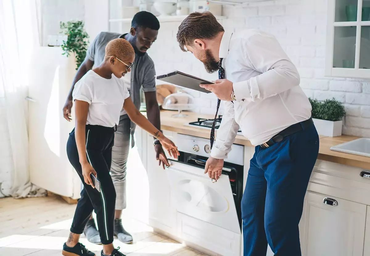 Specialist Showing Couple an Oven in a Modern Kitchen