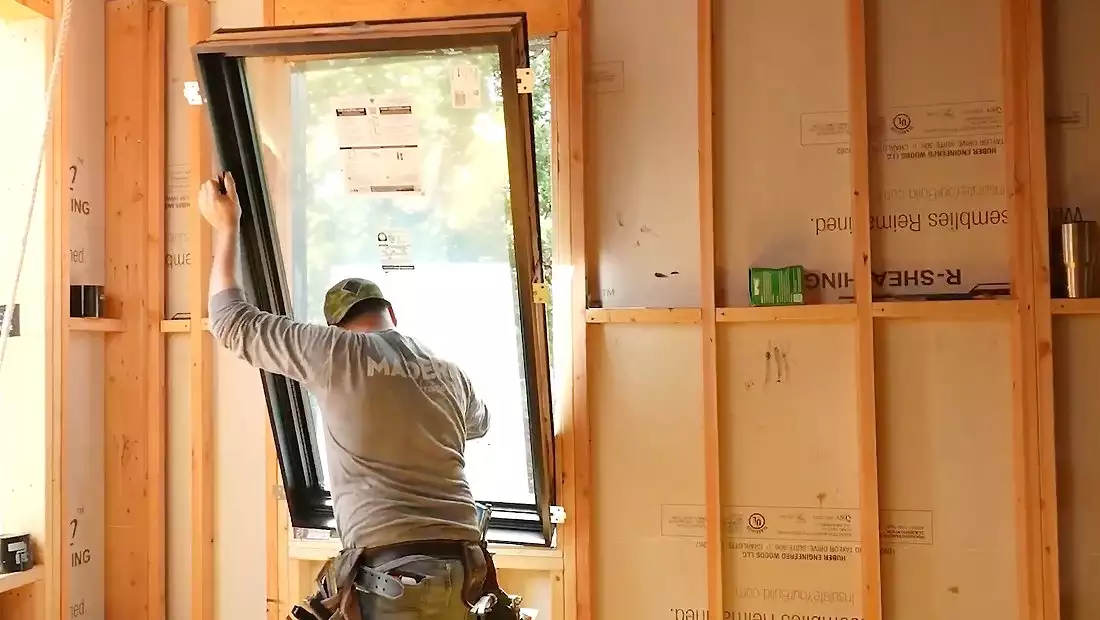 Worker Placing Window from Within the Austin Build House